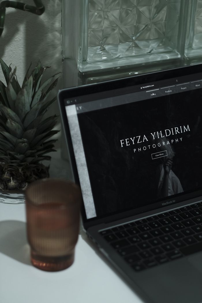 who-we-are An aesthetically pleasing workspace featuring a laptop with a photographer's website, surrounded by minimalist decor.