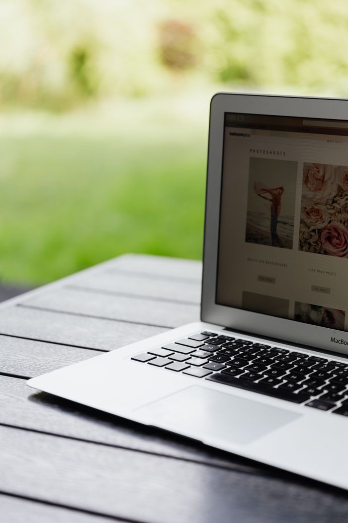 our-story Close-up of an open laptop on a table displaying a website outdoors.